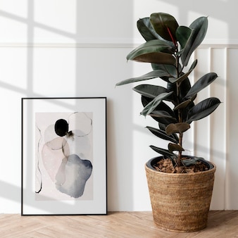 Picture frame mockup by a rubber plant on a wooden floor