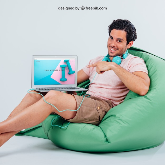 Smiley young guy pointing laptop's mock up