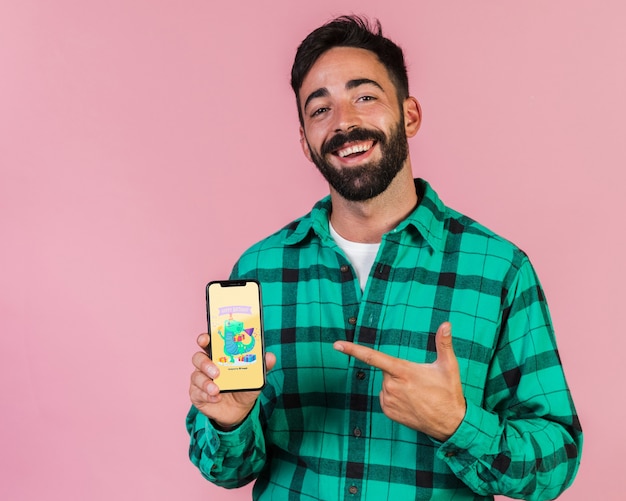 Smiling young man pointing finger at cell phone mock up