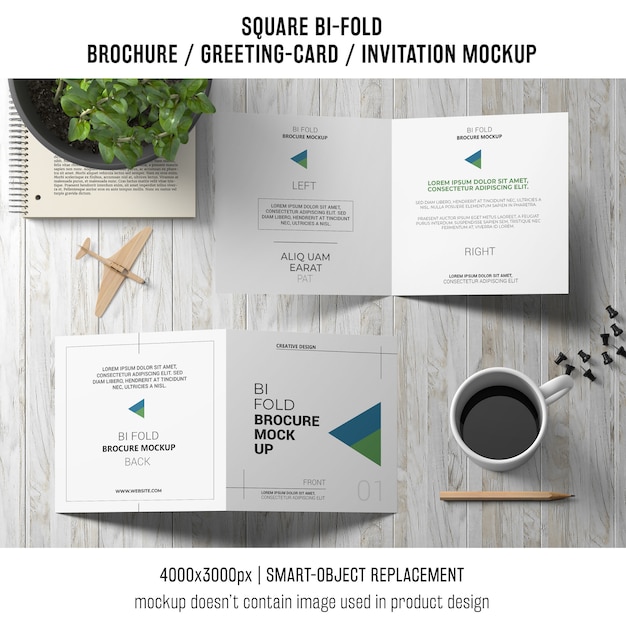 PSD gratuito opuscolo quadrato bi-fold o cartolina d'auguri mockup sul ripiano del tavolo in legno