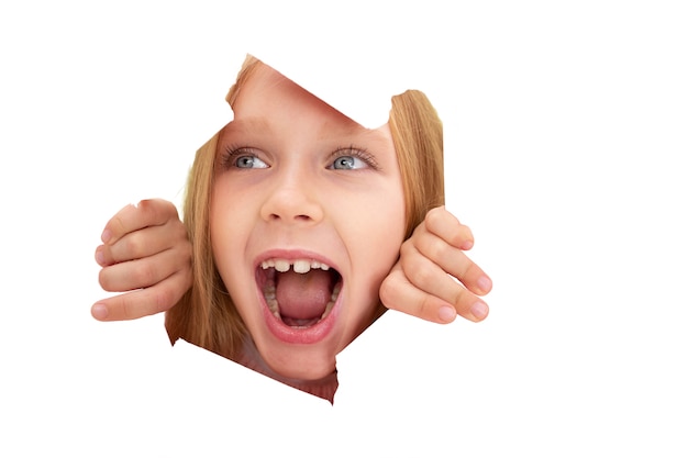 Studio portrait of young girl coming out of paper cut-out