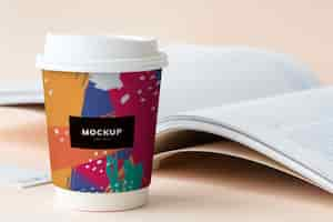 Free PSD takeaway coffee cup mockup on a table with an open book