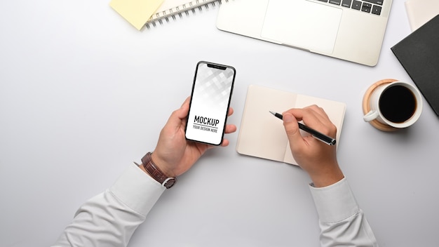 Top view of businessman hand working with smartphone mockup