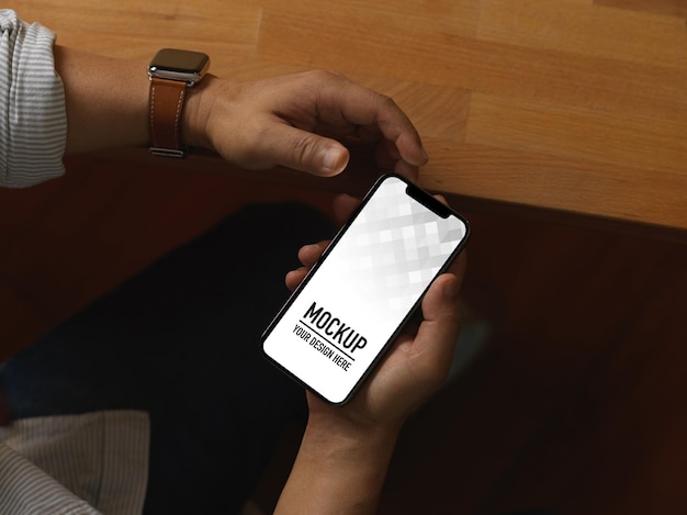 Top view of male hands using smartphone while sitting in office room