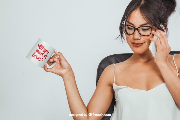 Woman holding a coffee mug's muck up and making a phone call