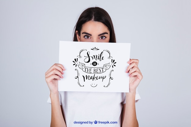 Woman holding paper with message in front of face