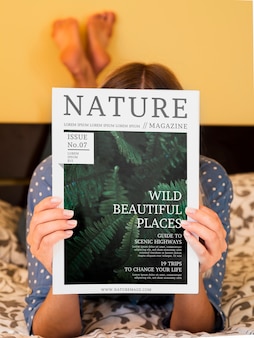 Женщина в постели показывает журнал о природе