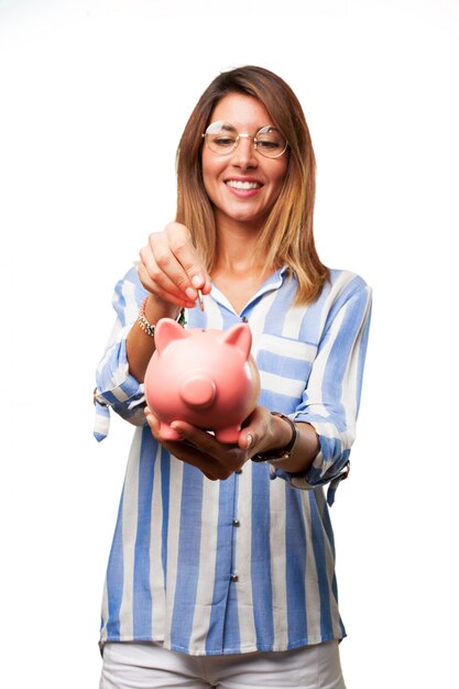 Woman inserting a coin into piggy bank