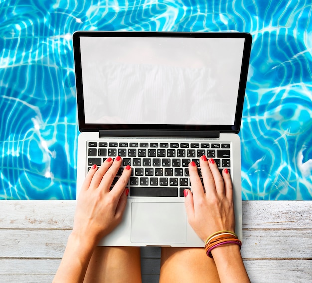 Woman using laptop at swimming pool