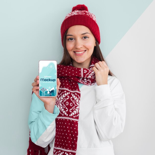 Woman wearing a hoodie and holding a phone mock-up