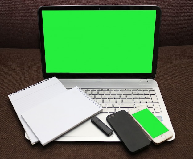 PSD gratuito schermo del computer portatile verde e smartphone con il blocco note a spirale e flash drive