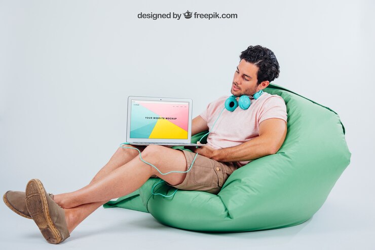 Free PSD young guy sitting with earphones and laptop's mock up