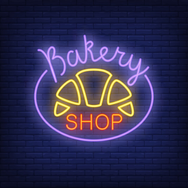 Free vector bakery shop neon sign. bright croissant on dark blue brick wall.