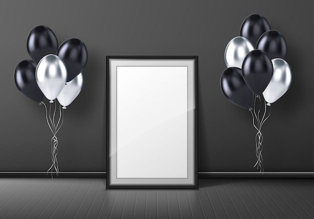 Black photo frame standing on gray background in empty room with balloons