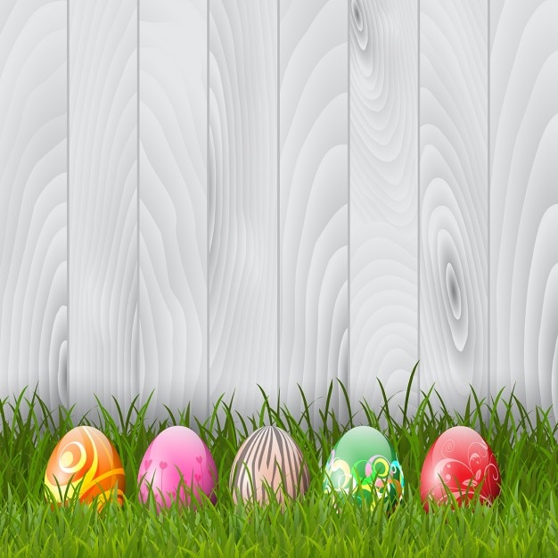 Decorative Easter eggs in grass on a wood background