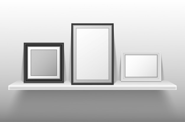 Empty photo frames standing on white shelf