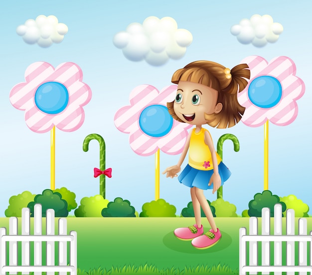 Una bambina vicino al recinto di legno con caramelle giganti
