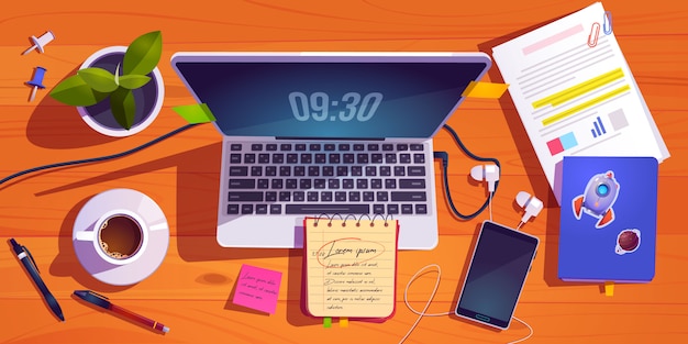 Top view of workspace with laptop, stationery, coffee cup and plant on wooden table.