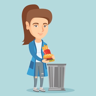 Женщина, выбрасывающая нездоровую пищу в мусорный бак.