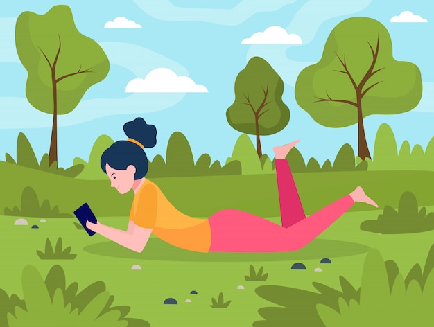 スマートフォンで草原に横たわっている若い女性