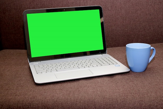 Blank screen laptop mit einem teetasse auf einem braunen hintergrund