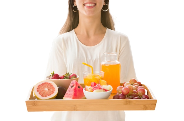 Blick auf eine frau, die ein tablett mit frischen früchten und saft hält