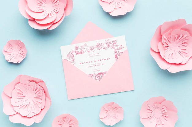 Hochzeitseinladungsmodell mit papierblumen auf blauem hintergrund