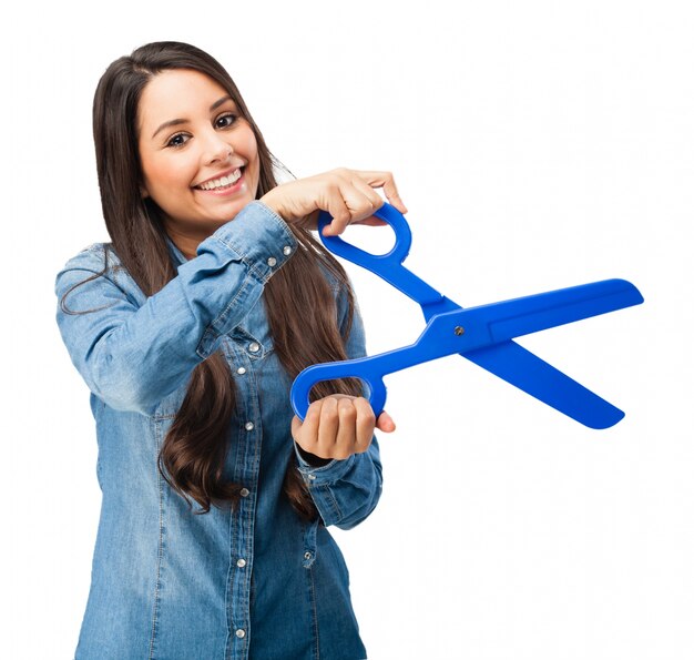 Junge Frau, die eine blaue Kunststoff-Schere halten