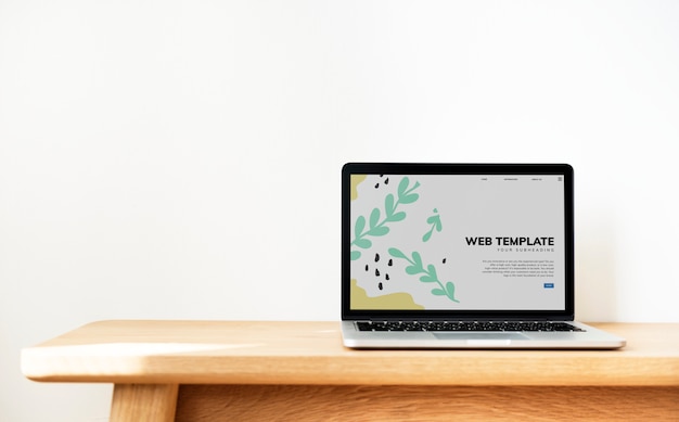 Laptop, der websiteschablone auf einem holztisch zeigt