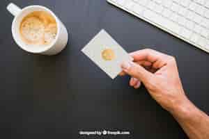 Kostenlose PSD mock up of hand halten visitenkarte mit kaffee und tastatur