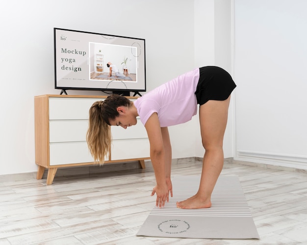 Sportliche frau, die yoga zu hause macht Premium PSD
