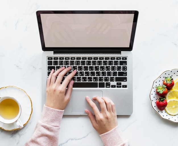 Vogelperspektive der Frau, die einen Laptop auf einer Marmortabelle mit Designraum verwendet