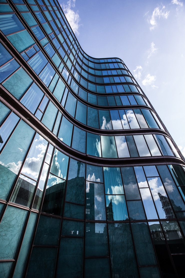 Gratis Foto a high rise building in a glass facade with the reflection of the surrounding buildings