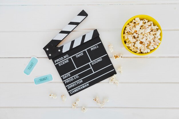 Clapperboard near popcorn and cinema tickets