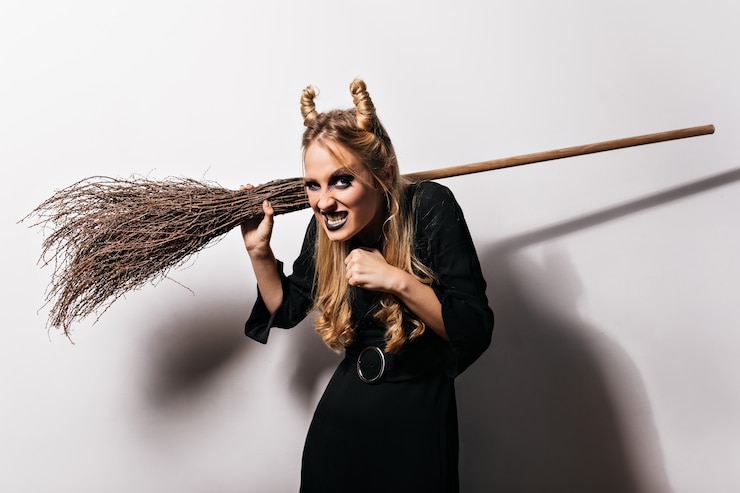 Gratis Foto evil witch making funny faces on white wall. indoor photo of fair-haired vampire girl.