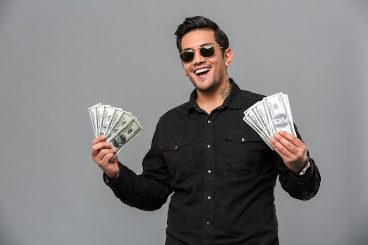 Gratis Foto excited young handsome man holding money.