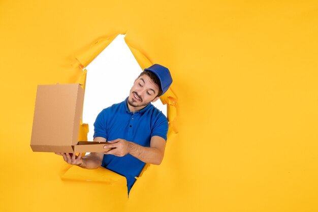 front view male courier holding opened pizza box on yellow space
