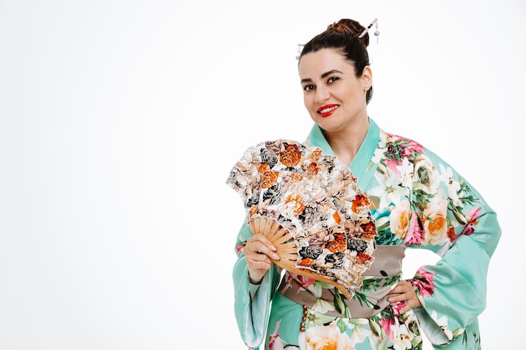 Gratis Foto happy woman in traditional japanese kimono holding hand fan smiling cheerfully on white