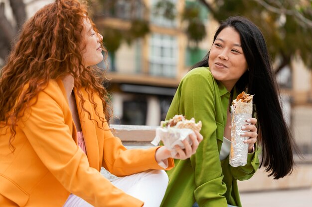 Happy women eating together street food