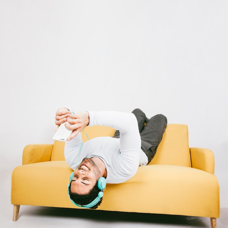 Gratis Foto happy young man on the sofa with phone and earphones