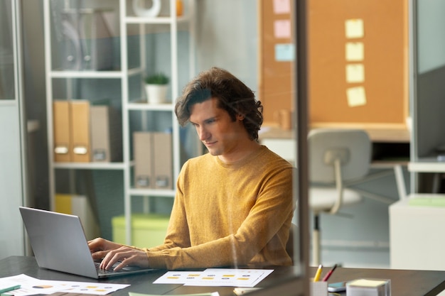 Mellomdistansebilde av en mann som jobber på en laptop