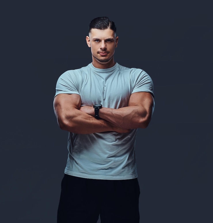 Gratis Foto portrait of a muscular handsome bodybuilder in sportswear, standing with crossed arms in a studio. isolated on a gray background.