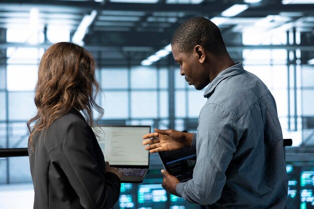 Server room IT staff members code on notebook doing maintenance