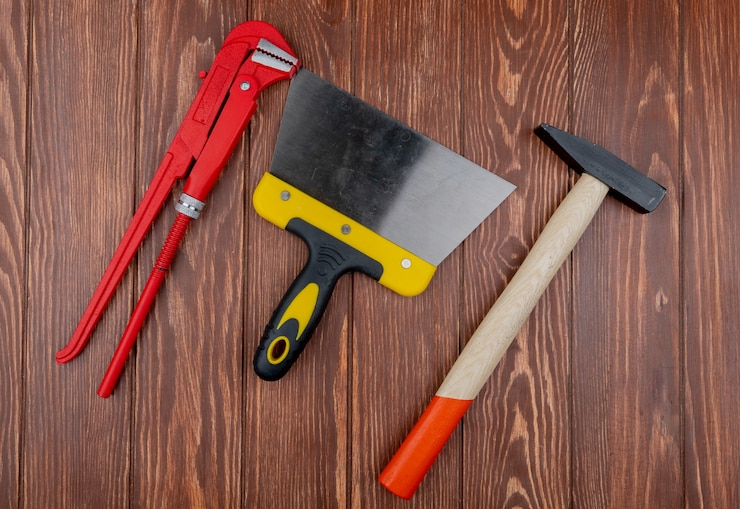 Gratis Foto top view of construction tools as wrench putty knife and brick hammer on wooden background