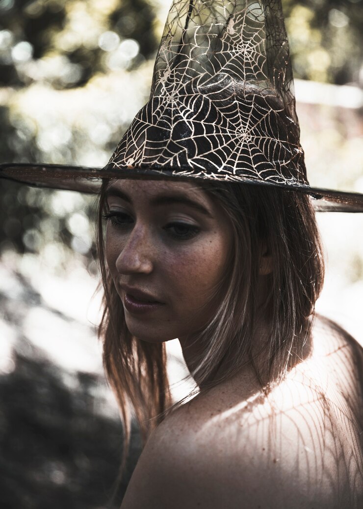 Gratis Foto young attractive woman in witch hat in murk forest