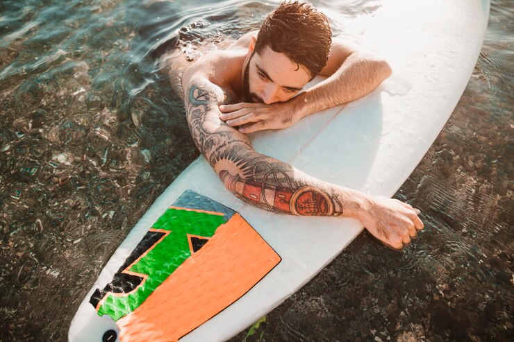 Gratis Foto young man lying on surf board in water