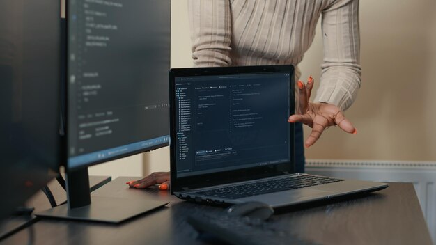 Closeup of laptop running algorithm parsing code on desk in front of programmers doing team work on group project. Portable computer compiling database in software developing office.