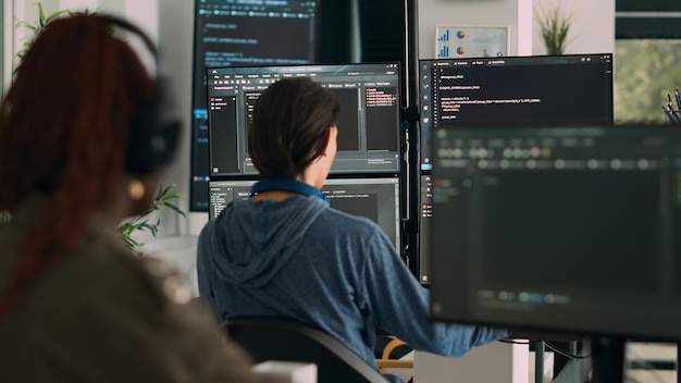 Database programer writing code on terminal window using multiple monitors in it agency office. System software developer typing database information, computing big data script.