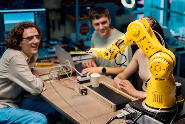Group of young people doing experiments in robotics in a laboratory Robot and tools on the table