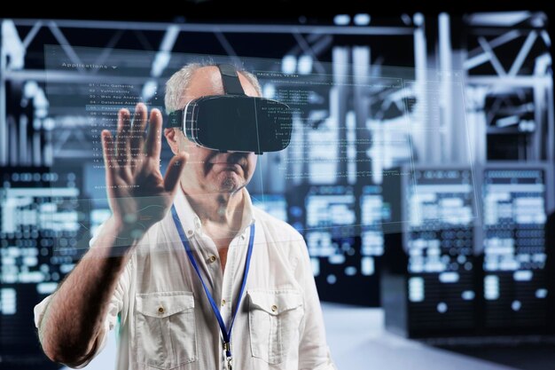 octogenarian manager immersed in virtual reality at data center, doing equipment maintenance. supervisor using vr headset to optimize server system performance, checking code lines